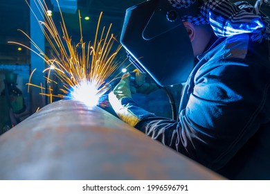 Welder working with electrode at semi automatic arc welding in manufacturing production plant. Welding method MIG.
