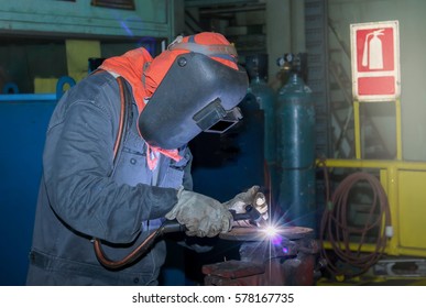 Welder Working A Welding Metal Pipe With Protective Mask And Sparks In Factory On Night Shift
