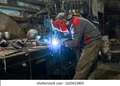 Welder Works In A Small Cluttered Private Workshop