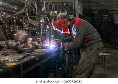 Welder Works In A Small Cluttered Private Workshop