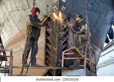 Welders on black metal, repairing a ship in dry dock - Powered by Shutterstock