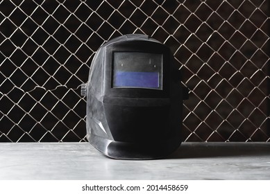 Welding Helmet Close Up On The Metal Workbench Background. Front View.