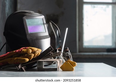 Welding Helmet On The Metal Workbench Background.