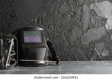 Welding Helmet On The Metal Workbench Background.