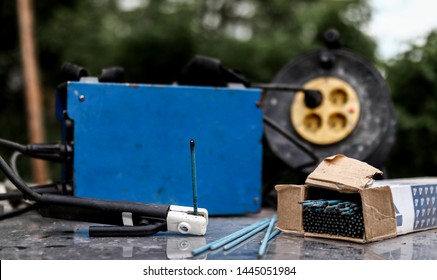 Welding machine, electrical power extension cable reel and blue electrodes in a cardboard box on a metal table