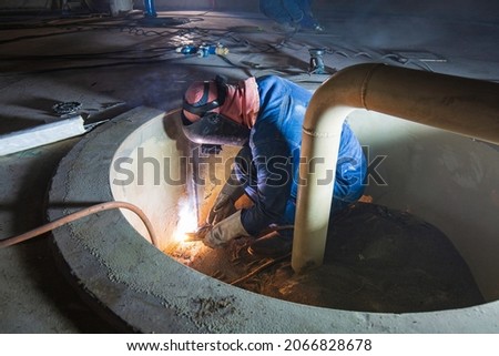 Welding male worker metal is part in machinery tank plate bottom sump  oil storage tank inside confined spaces.