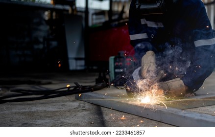 Welding, male worker welding metal workpiece outside factory, protective clothing protective gloves and safety helmet, welding sparks and light - Shutterstock ID 2233461857