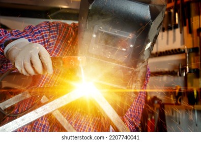 Welding Of Metal Construction With Flash Light And Sparks. Welder Man In Work. Locksmith With An Electrode In Hand. Metalwork Production Factory. Heavy Industry Concept.