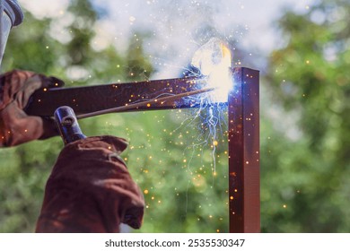 Welding Metal Frame. Welder Craftman's Hand Welds Metal Frame of Fence with Sparks and Smoke on Green Nature Background Close up.	 - Powered by Shutterstock