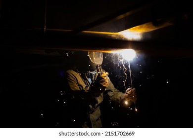 Welding Of Metal. Worker In Mask And Gloves. Bright Light And Sparks. Black Background.