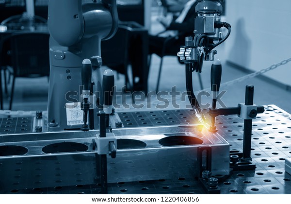 The welding robot machine for welding automotive\
part in the light blue scene.Industrial 4.0 concept for modern\
manufacturing process.