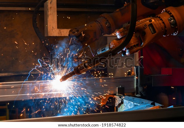 Welding robot, welds metal\
beams. Modern welding production. Bright flashes, sparks and\
smoke.