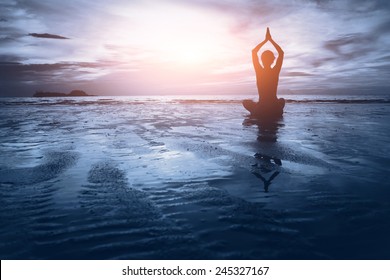 well being concept, beautiful sunset on the beach, woman practicing yoga