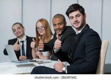 Well done business project. Portrait of confident and motivated businessman working on the project with his team with a smile. All are wearing formal suits. Office business concept