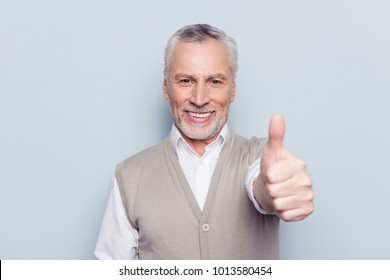 Well done! Close up portrait of delightful confident cool glad pleased cheerful excited grandpa demonstrating thumb-up knitted beige waistcoat beaming smile isolated on gray background