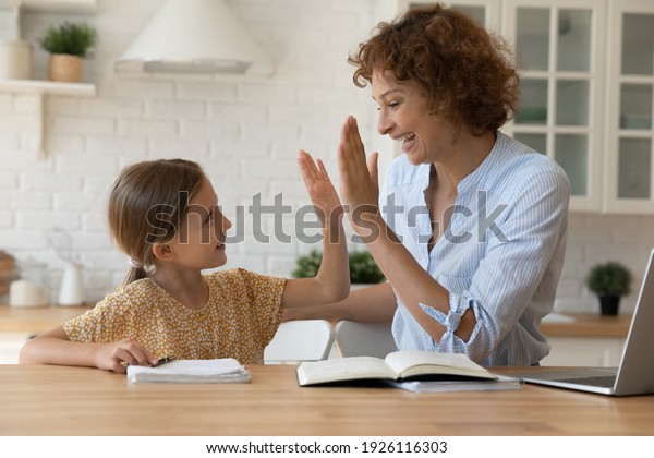 Well done dear. Excited mother give high five to\
small daughter praise child for reaching success in homework.\
Joyful female tutor greet schoolgirl for giving correct answer\
solving hard math problem