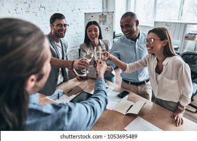 Well done everybody! Top view of young business people toasting each other and smiling while standing in the board room           - Powered by Shutterstock