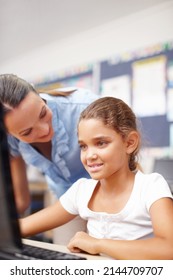 Well Done, Keep It Up. A Beautiful Young Teacher Assisting A Cute Schoolgirl In Computer Class.