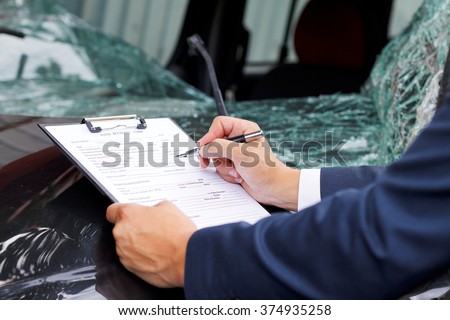 Well dressed insurance assessor inspecting damaged vehicle