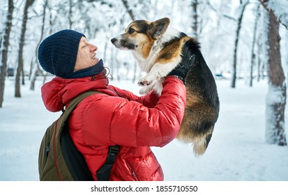 Well Dressed Man Enjoying Snowy Winter With Welsh Corgi Dog. Pets, People And Season Concept.