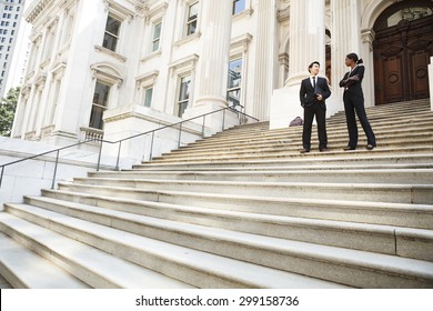 A well dressed man and woman converse on the steps of a legal or municipal building. Could be business or legal professionals or lawyer and client. - Shutterstock ID 299158736