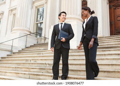 A well dressed man and woman smiling as they as they walk down steps of a courthouse  building. Could be business or legal professionals. - Shutterstock ID 1908076477