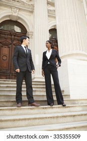 A well dressed man and woman standing on the steps of a stately building in discussion. Could be legal, political or business professionals. - Shutterstock ID 335355509