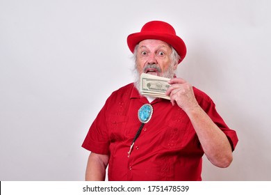 Well Dressed Old Man Wearing A Red Derby Hat, Red Shirt And Large Bolo Tie Loves His Money So Much He Is Licking It.
Greedy Old Man Licking His Money.