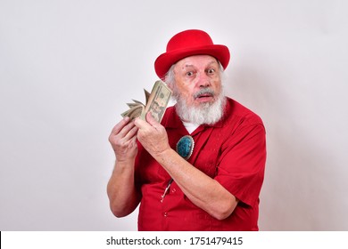 Well Dressed Old Man Wearing A Red Derby Hat, Red Shirt And Large Bolo Tie Is Fanning Himself With His Money.
Greedy Old Guy Is Enjoying The Cold, Hard Cash
