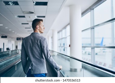 Well Dressed Young Man Travel By Airplane. Businessman With Luggage Walking On Travelator At Airport.