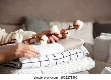 Well groomed woman hands holding the cotton branch with pile of neatly folded bed sheets, blankets and towels. Production of natural textile fibers. Manufacture. Organic product. - Shutterstock ID 1832271592