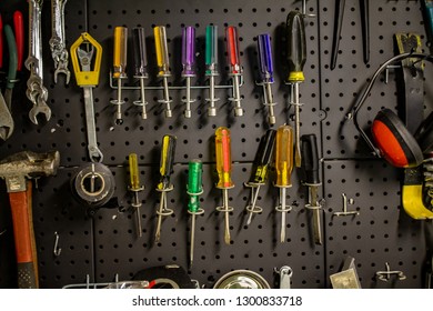 A Well Organized Black Metal Peg Board Filled With Tools. Includes Screwdrivers,  Wrenches, Hammers, Electrical Tape.