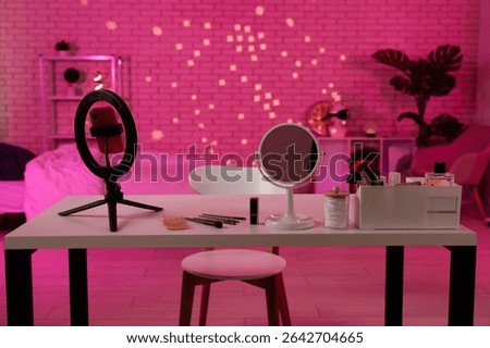A well organized makeup table with essentials, perfect for creating beauty content in a cozy, pink lit room.