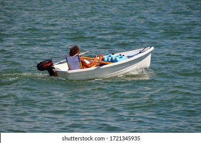 
Well Tanned Gay Man Leisurely Cruising In A Tiny White Outboard Engined Powered Dingy.