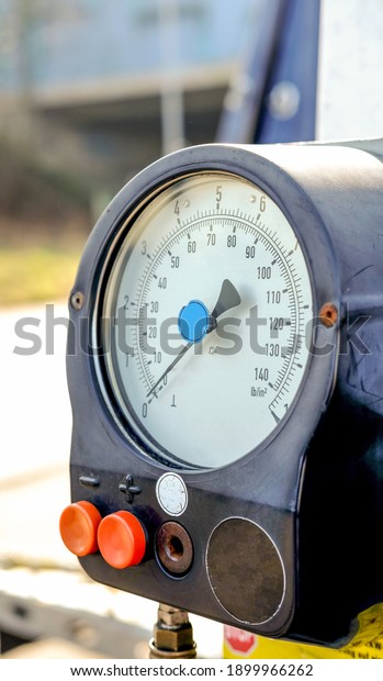 Well used tire pressure\
gauge at a gas station near a street - selective focus and blurred\
background 
