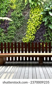 A well-arranged vertical garden with a wooden fence and floor in the foreground, complete with wooden chairs, giving a natural, modern, and tidy impression, along with bright natural lighting    - Shutterstock ID 2370009235