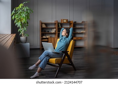 Wellbeing for self-employed freelance workers. Happy smiling female freelancer with laptop on knees relaxing with hands behind head and closed eyes, remote employee feeling satisfied with work done - Shutterstock ID 2124144707