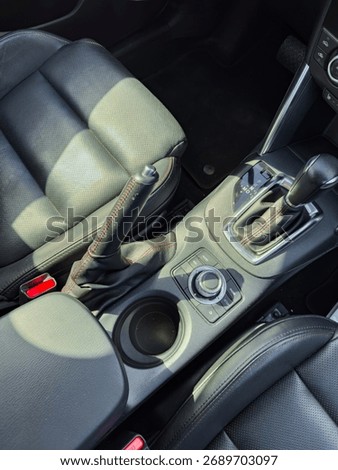 A well-designed car interior featuring a smooth gear shift, cup holder, and stylish seats, capturing the essence of comfort during a joyride on a bright day.