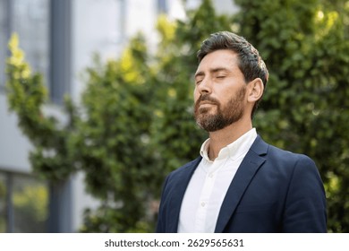 Un hombre bien vestido con los ojos cerrados disfruta de un momento de paz al aire libre, rodeado de vegetación, con aspecto tranquilo y sereno.