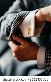 A well-dressed man pulls back his suit jacket sleeve to reveal a golden cufflink in the shape of a dragon