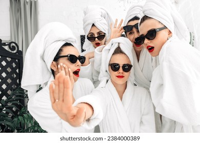 Well-groomed girls get together to celebrate a bachelorette party. Women after spa treatments, wrapping their heads in a towel, enjoy the fun. Concept of entertainment and spa treatments for women. - Powered by Shutterstock