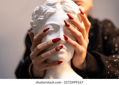 well-groomed nails. Patterned red nails close-up. female hands holding statue