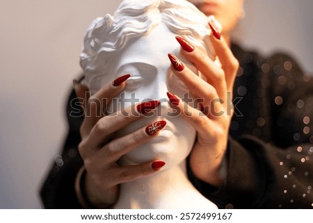 well-groomed nails. Patterned red nails close-up. female hands holding statue