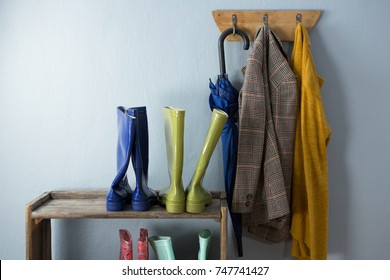 Wellington boots, umbrella and blazer on hook against wall