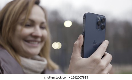 Wellington, New Zealand - 11.13.2020: Young Smiling Woman Having A Video Call And Talking To Someone, Looking At The Smartphone. Action. Female Holding Apple Iphone 12 Pro Max In Pacific Blue Color.