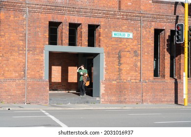 Wellington New Zealand - July 31 2021; Woman In Green Top Shield Eyes From Sun As She Enters Gallery Opening Into Street Of Heritage Wool Shed Known As Shed 21 On Waterloo Quay, Wellington