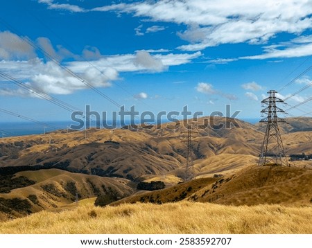 Similar – Foto Bild Windräder in hügeliger Landschaft mit Bäumen und abgeernteten Feldern / Frühherbst