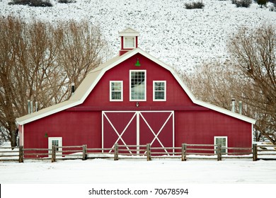 A well-kept, classic red barn in a rural winter setting in Utah, USA.