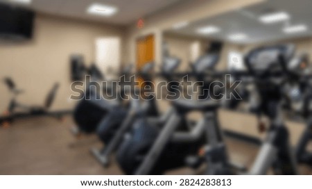 A well-lit gym interior featuring rows of modern stationary exercise bikes and other cardio machines, ready for a workout.