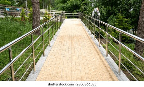 A well-maintained, accessible pathway lined with stainless steel railings, surrounded by lush greenery.